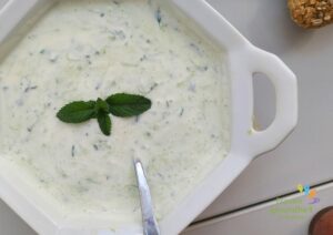 weiße Schüssel mit Gurken-Joghurt und Minzblatt-Dekoration