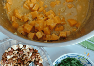 ein Topf mit Süßkartoffelcurry und einer Schale geröstete Haselnüsse als Topping