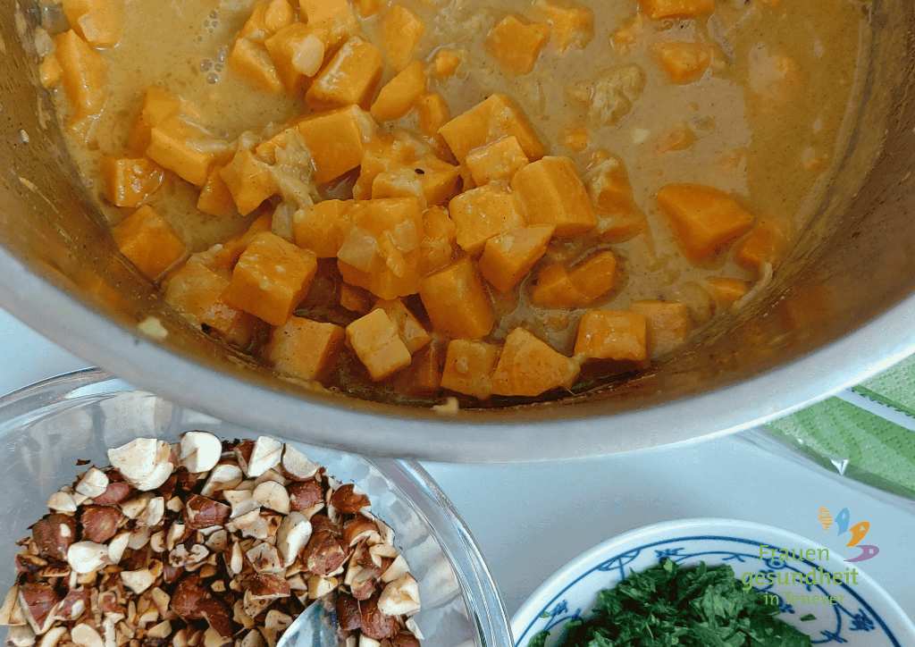 ein Topf mit Süßkartoffelcurry und einer Schale geröstete Haselnüsse als Topping